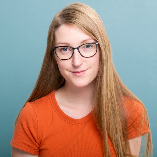 Julia Nance - portrait of the photographer on blue background wearing orange T-shirt
