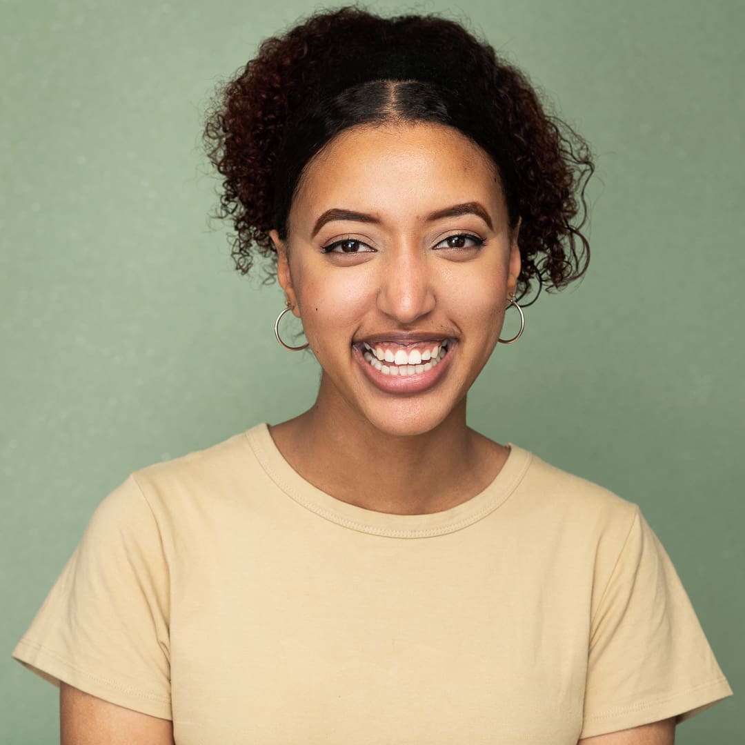 Woman photographed on a green background in a studio smiles for an actor headshot.
