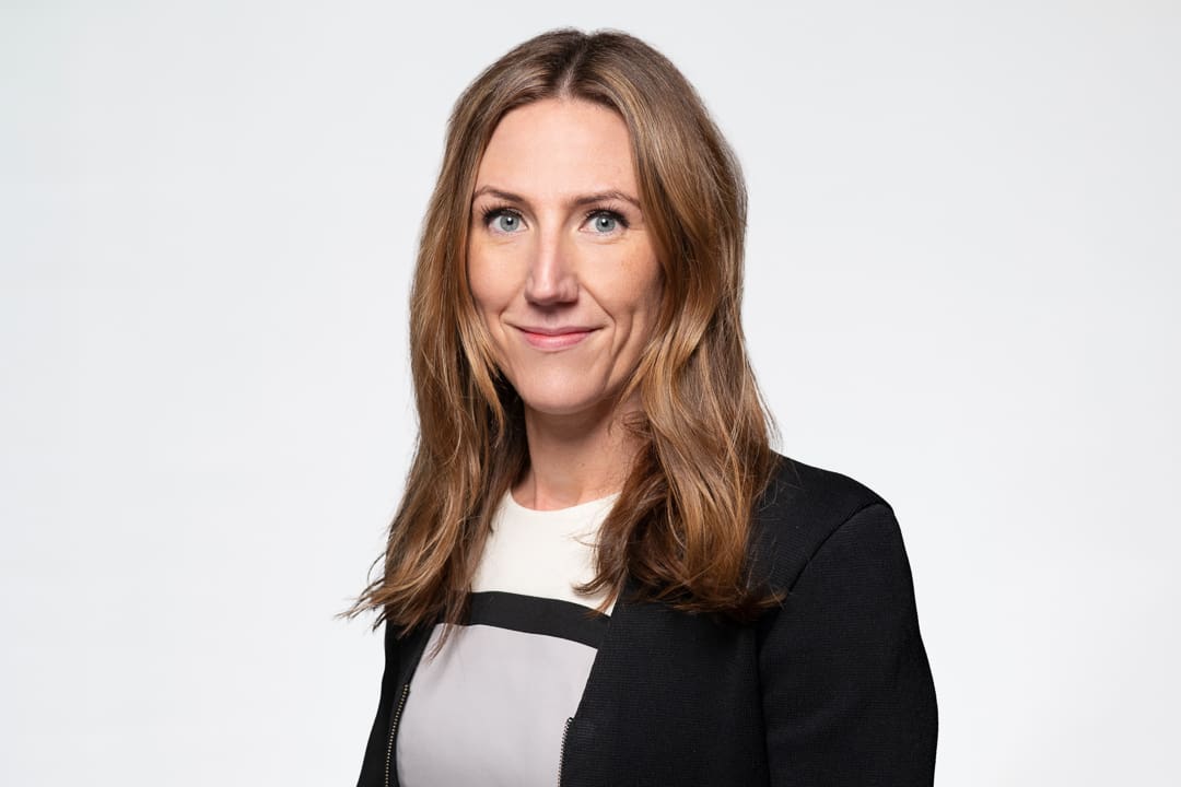 Melbourne barrister headshot of woman wearing a white dress and black blazer, smiling to camera confidently.
