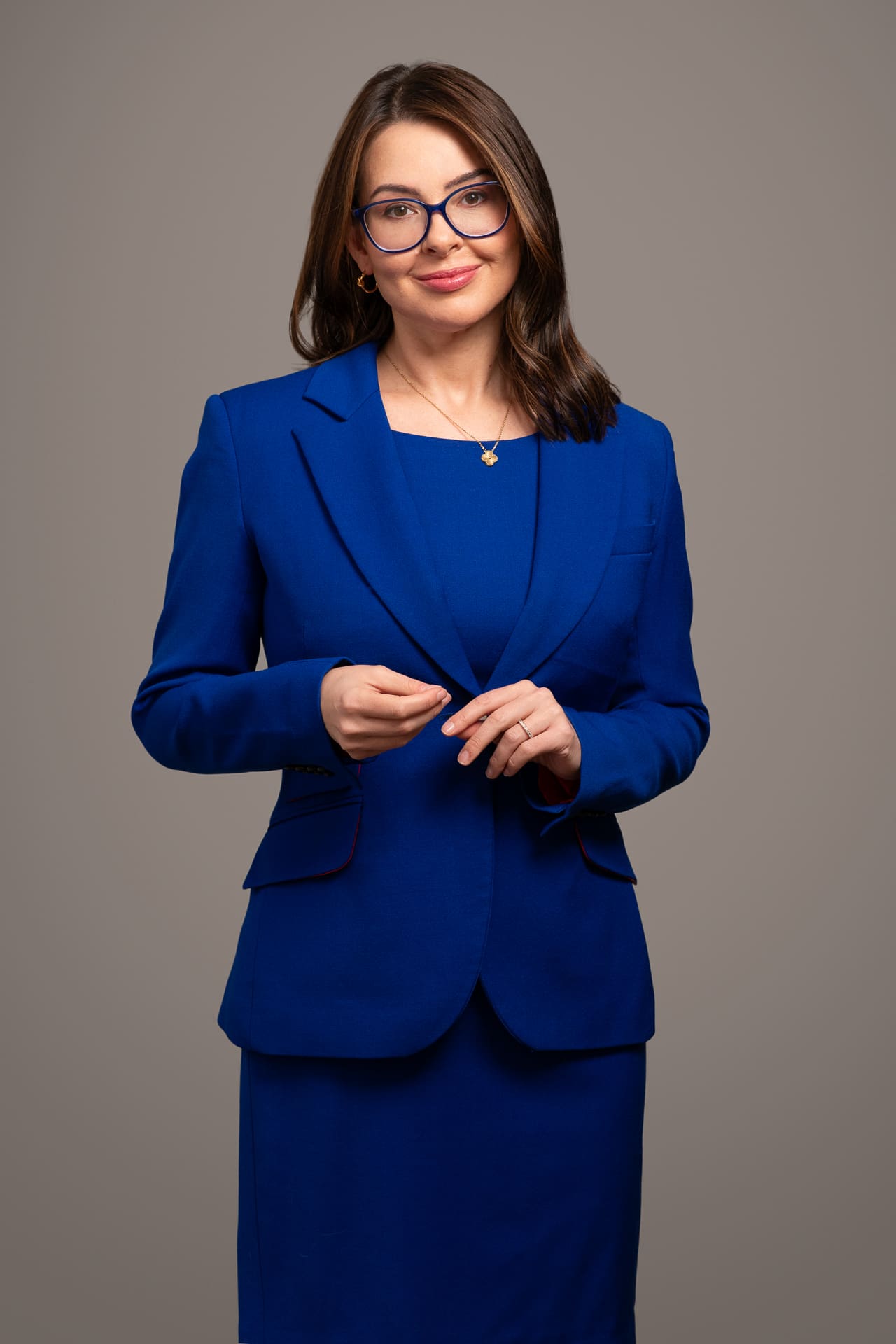 Executive corporate portrait of woman standing in studio setting, with royal blue suit jacket and skirt on.