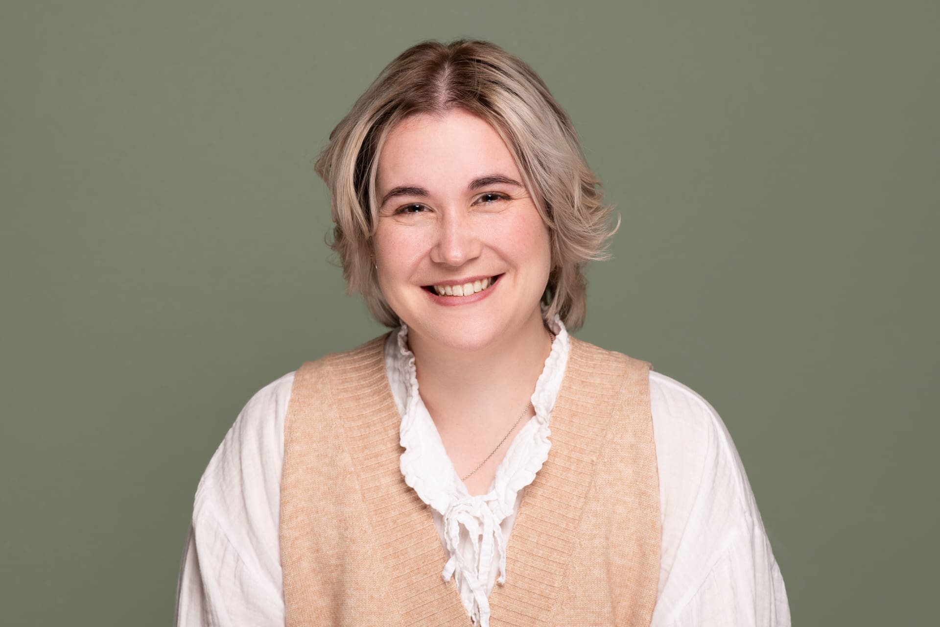 Personal branding headshot on a green background, smiling to camera.