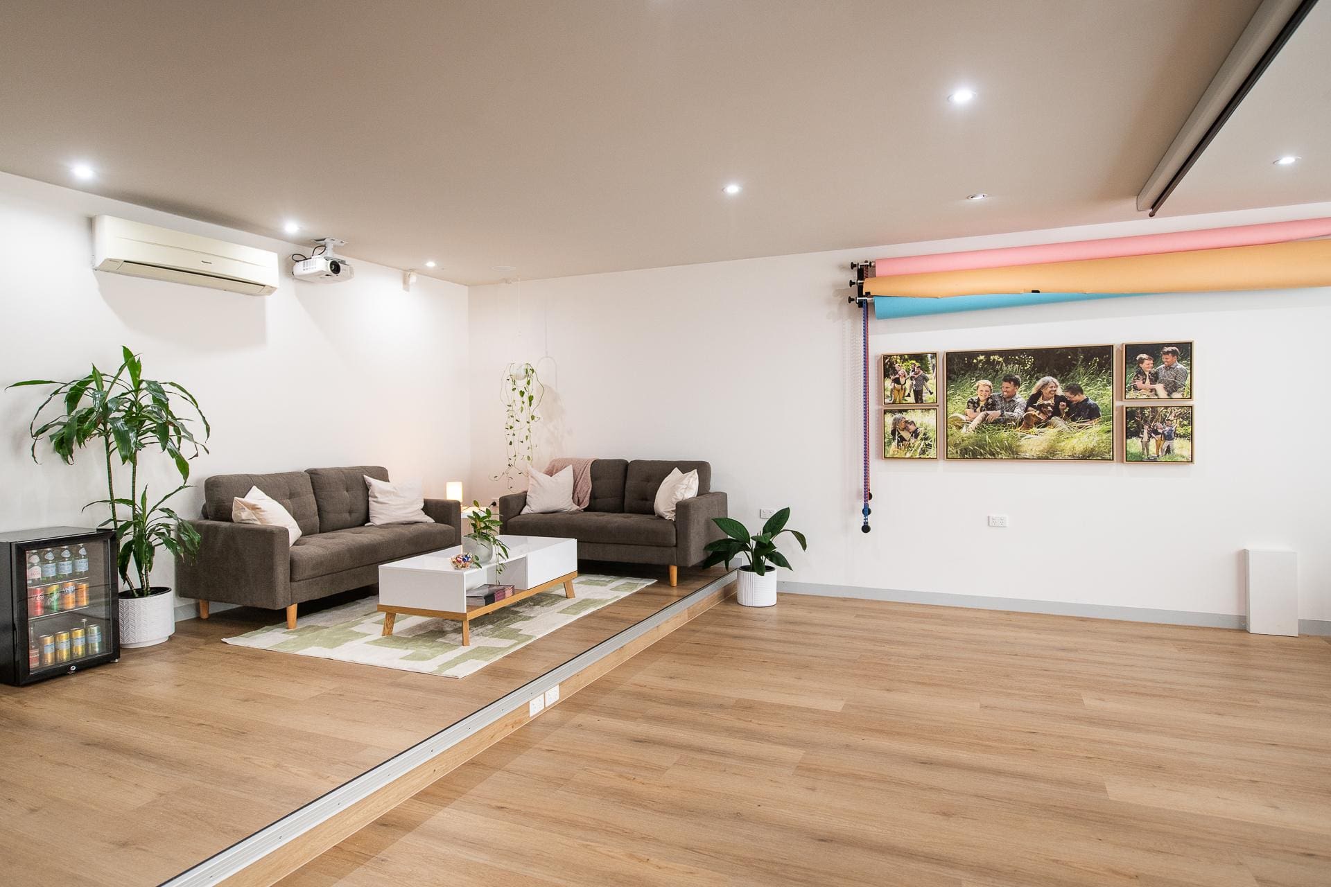 Interior image of the Julia nance Portraits studio. On the left are two couches and a coffee table, as well as plants and a drink fridge. On the right is open space, artwork and photography backgrounds.