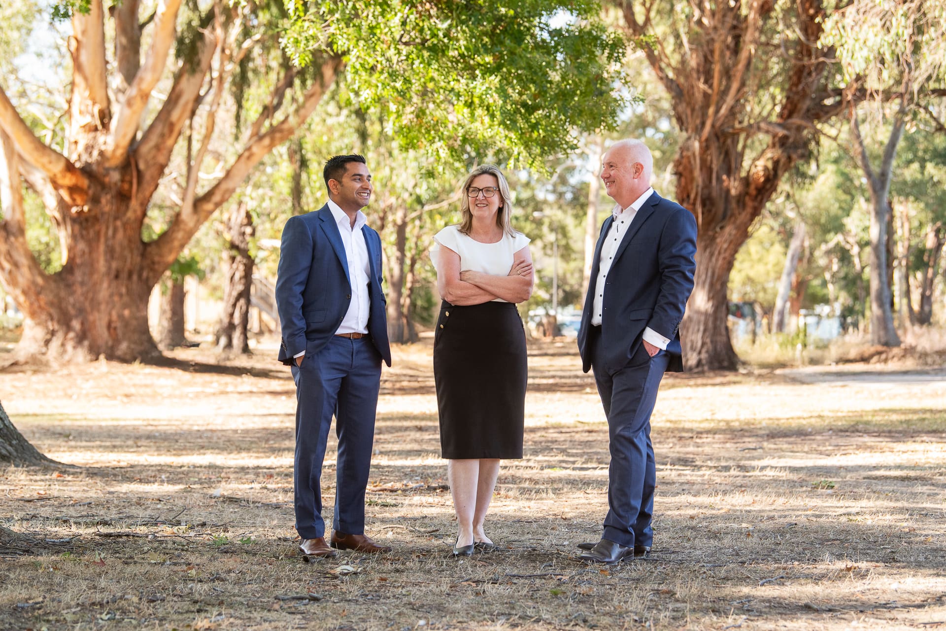 Relaxed team portrait taken outdoors, three people smiling and not looking to camera.