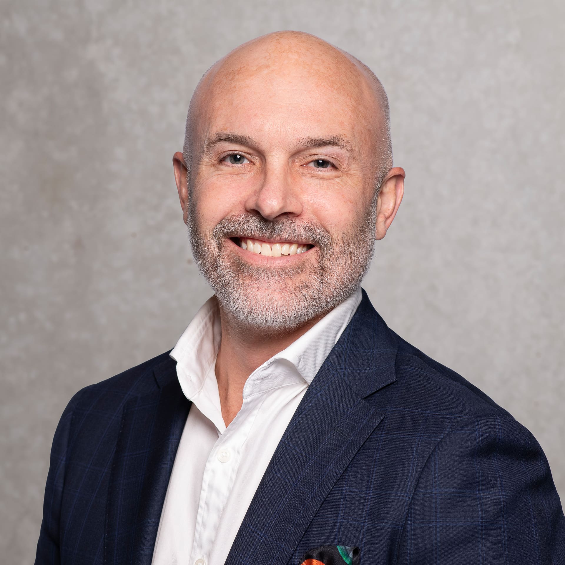 Man smiles to camera for corporate portrait on textured background.