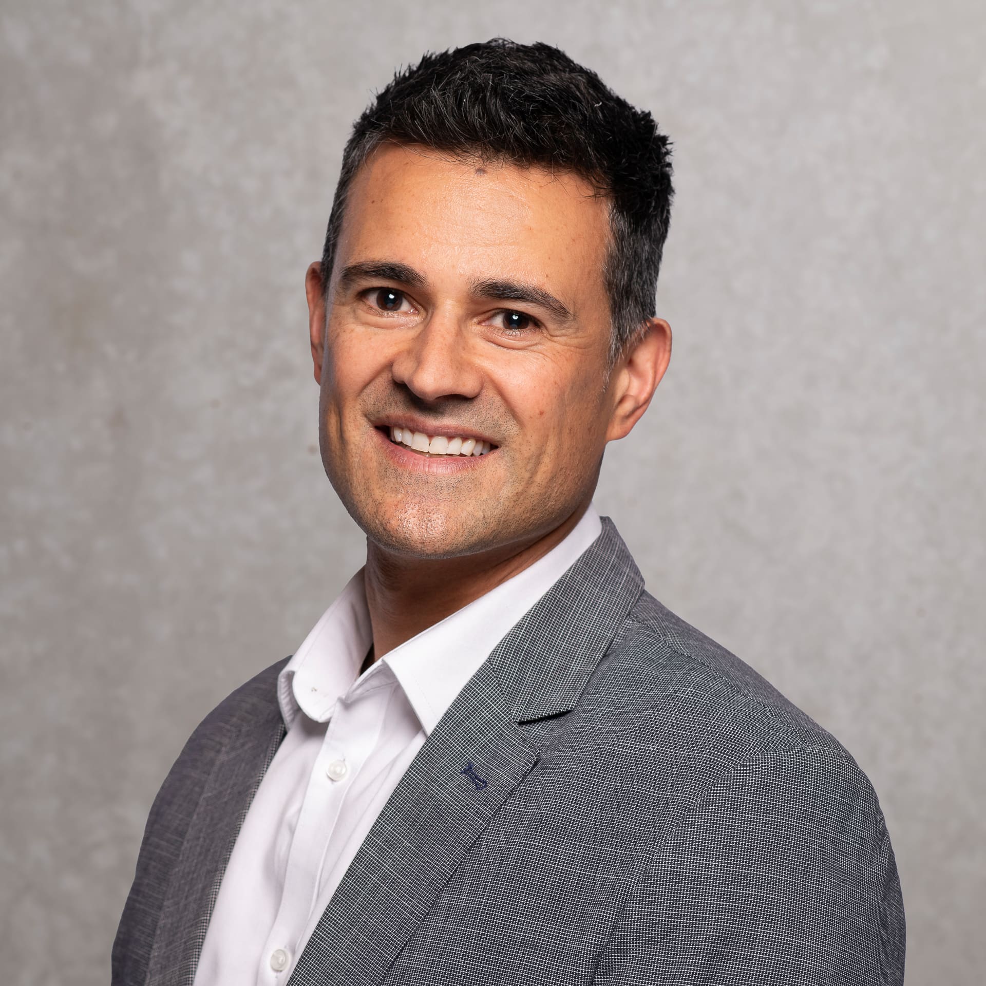 Man smiles to camera for corporate portrait on textured background.