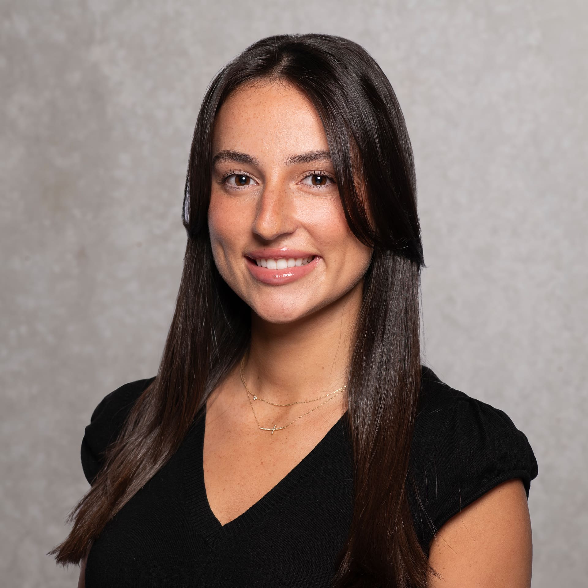 Woman smiles to camera for corporate portrait on textured background.