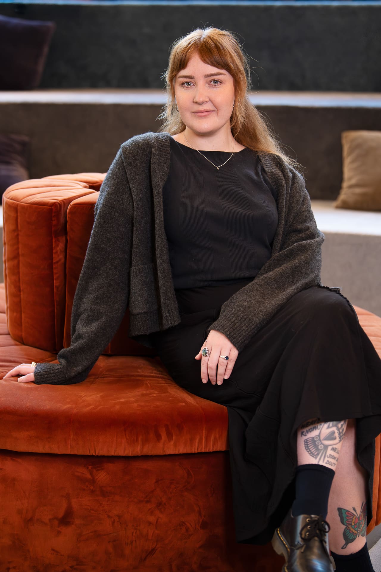 Relaxed portrait of staff member seated down, leaning on one arm.