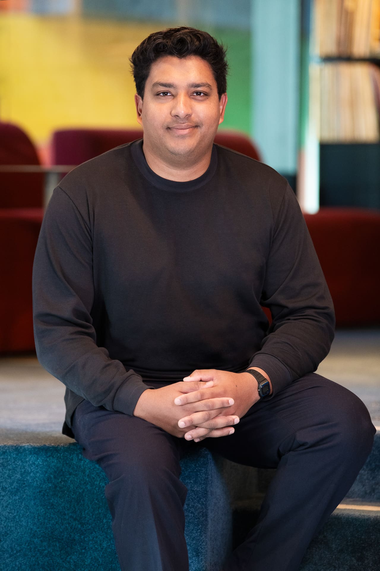 Seated portrait of a man in colourful interior, with a soft expression.